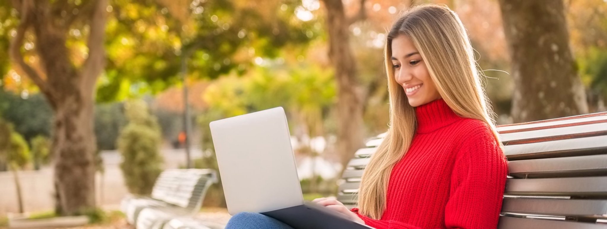 Beautiful girl seating in the park using a laptop